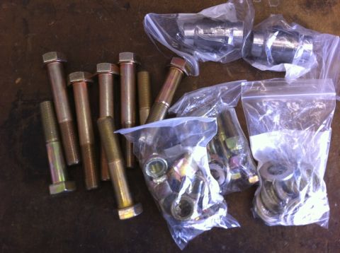 1987 Suzuki Samurai - Various bolts and suspension components are laid out in plastic bags on a dark surface.