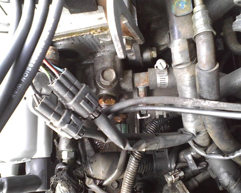 Engine bay with electrical connectors and hoses. Text reads SUPERMOTORS.NET