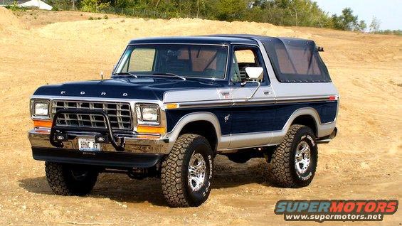 Blue and silver Ford Bronco with a black soft top, chrome bumper, and bull bar