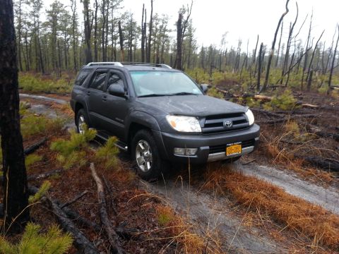 1987 Toyota 4Runner - Toyota 4Runner parked on a muddy dirt road in a forest with burnt trees.