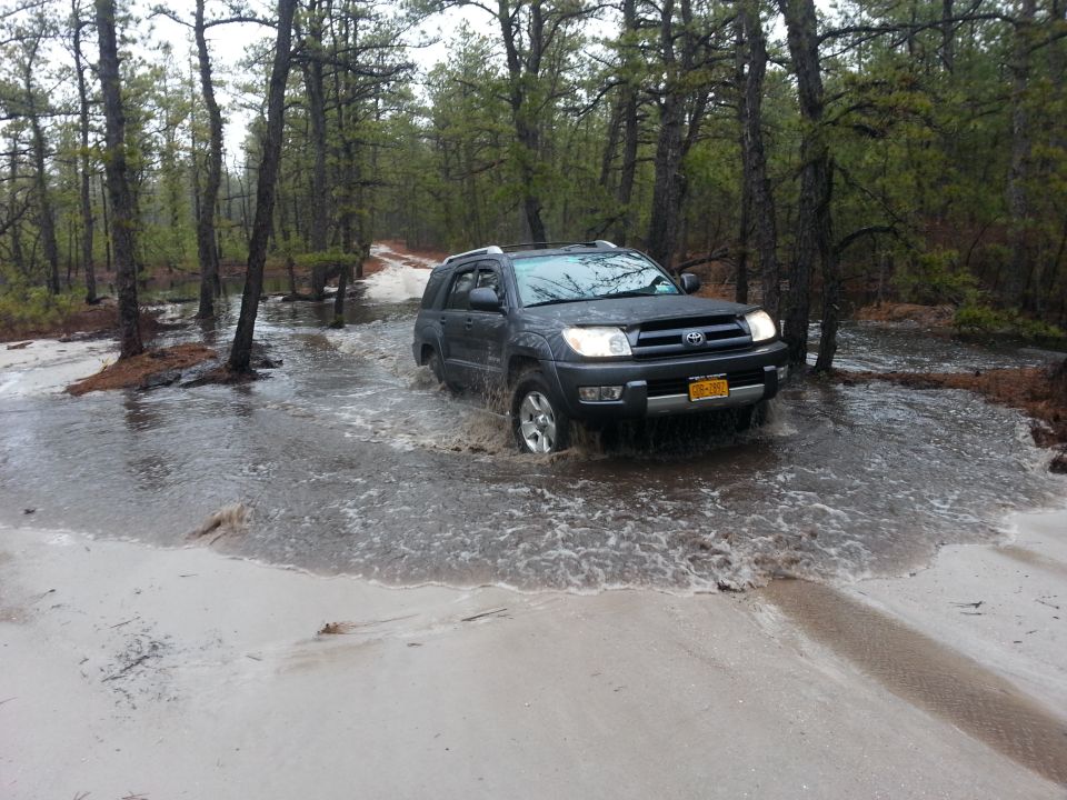 Dark SUV driving through flooded dirt road in Wharton State Forest