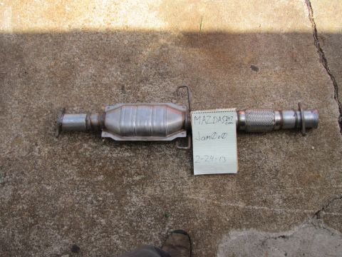 1995 Ford Bronco - A catalytic converter assembly is laid out on a concrete surface, with a handwritten note attached.