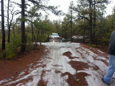 1987 Toyota 4Runner - White 1987 Toyota 4Runner navigates a muddy, water-filled dirt track in a forest.