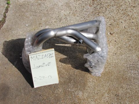 1995 Ford Bronco - An exhaust manifold is shown wrapped in bubble wrap next to a notepad with writing on it.