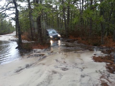 1987 Toyota 4Runner - A 1987 Toyota 4Runner tackles a challenging off-road path through a wet, wooded environment.