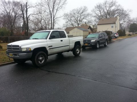 1987 Toyota 4Runner - Two vehicles are parked on a wet residential street on an overcast day.