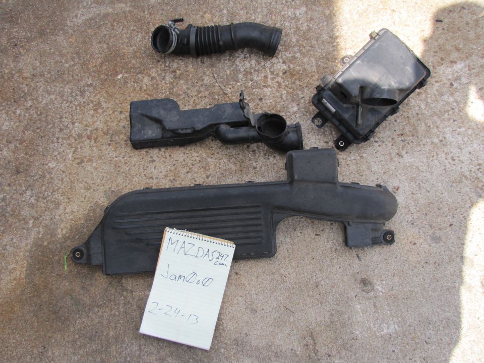 Mazda air intake parts on concrete, with handwritten note