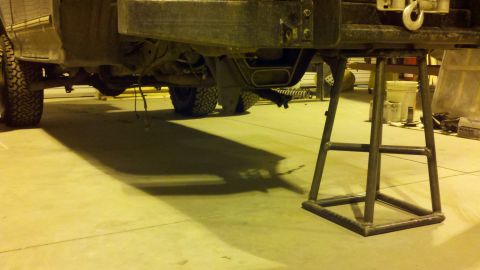 1996 Ford Bronco - The rear of a vehicle is raised on a jack stand for maintenance in a workshop.