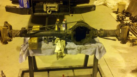 1996 Ford Bronco - A vehicle's differential axle assembly is shown disassembled on a workbench, with tools and cleaning supplies present.