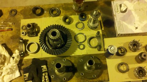 1996 Ford Bronco - Various automotive differential parts are spread across a wooden surface, including gears, bearings, and hubs.