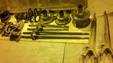 1996 Ford Bronco - Various drivetrain and suspension parts are laid out on the floor, including axles and a differential.