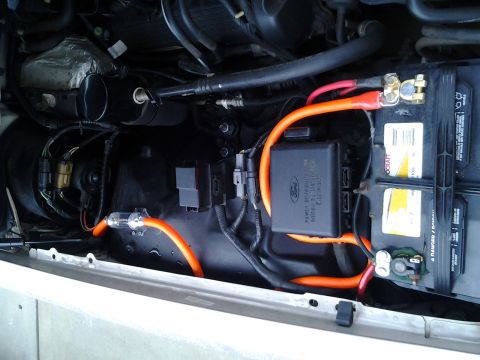 1998 Mercury Grand Marquis - Engine bay view showing a car battery, wiring, and a Ford fuse box.