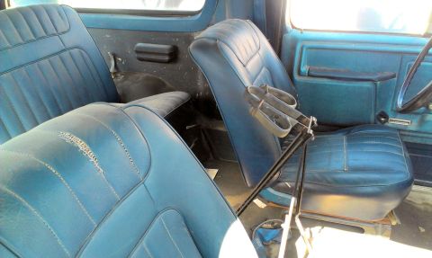 1994 Ford Bronco - Interior view of a vehicle showing worn blue seats and door panels.