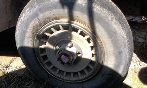 1994 Ford Bronco - Close-up of a worn tire and a multi-spoke wheel hub.
