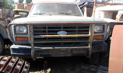 1994 Ford Bronco - Front view of a 1994 Ford Bronco, showing its grille and brush guard, parked among other vehicles.