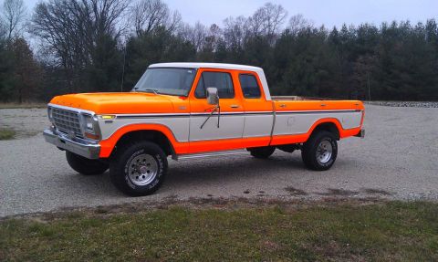 1994 Ford Bronco - Late-1970s Ford SuperCab long-bed 4x4 pickup in two-tone orange and white, shown from the front three-quarter on a gravel lot with bare win…