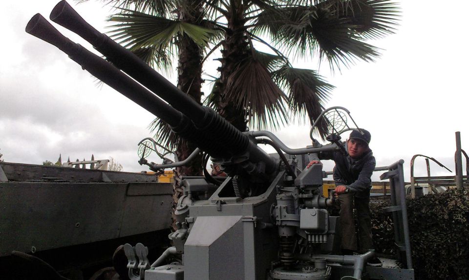 Twin barrel anti-aircraft gun with a person standing next to the controls