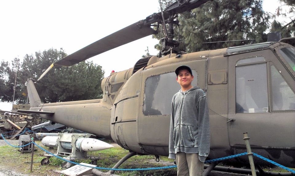 Kid standing next to a US Army helicopter with a missile attached