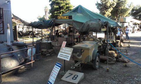 1994 Ford Bronco - A scene depicting a military encampment with various vehicles and equipment on display, including a camouflage trailer and tents.