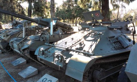 1994 Ford Bronco - Multiple military tanks are lined up outside, with one prominently displaying a red emblem on a raised metal plate.