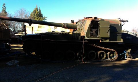 1994 Ford Bronco - A military self-propelled howitzer with tracks and a large cannon is parked outdoors.