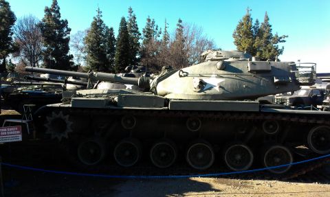 1994 Ford Bronco - A military tank is parked outdoors with other vehicles visible in the background.