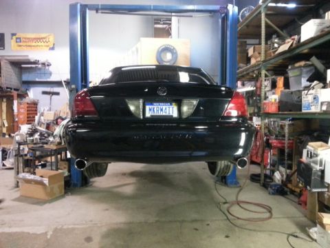 2004 Mercury Grand Marquis - Rear view of a black 2004 Mercury Grand Marquis on a car lift in a garage.