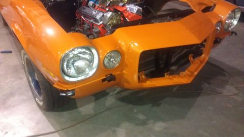 1973 Chevrolet Camaro - Front view of an orange 1973 Chevrolet Camaro undergoing restoration, showing the engine.