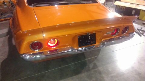 1973 Chevrolet Camaro - The rear of an orange muscle car with a spoiler and chrome bumper is shown.