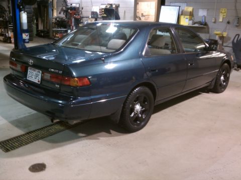 1998 Toyota Camry - A dark blue 1998 Toyota Camry sedan is parked in a garage, viewed from its rear-left quarter.