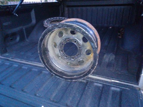 1968 Ford Bronco - Two old wheels sit in the cargo area of a pickup truck.