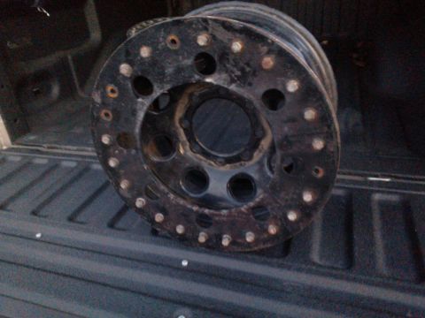 1968 Ford Bronco - A black wheel with many lug nut holes is shown, likely a replacement part for an off-road vehicle.