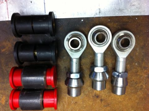 1987 Suzuki Samurai - A collection of suspension bushings and rod ends are laid out on a workbench.