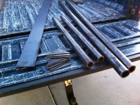 1987 Suzuki Samurai - Various metal components, including tubes and flat stock, are arranged on the textured surface of a truck bed.
