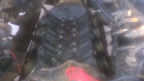 1990 Ford Bronco - Close-up view of an engine bay, black valve covers and surrounding components. A red rag is visible in the foreground.