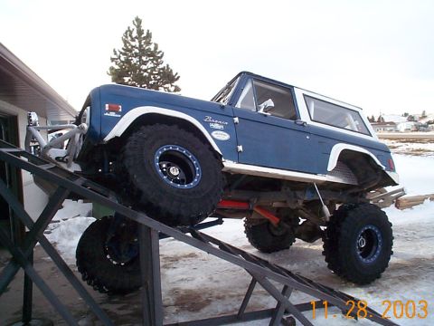 1977 Ford Bronco - A blue early Ford Bronco with a white hardtop, white fender flares and "Bronco" script badge climbs a steel RTI flex ramp in a snowy drivew…
