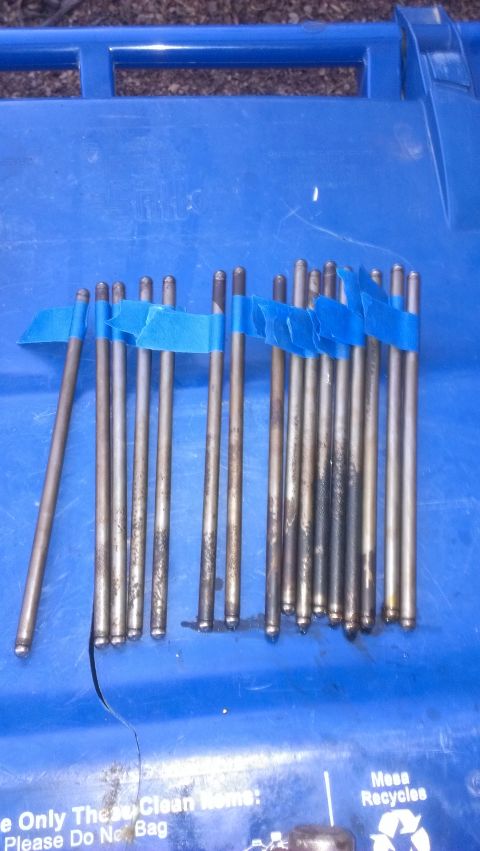 1990 Ford Bronco - A collection of valve lifters, some with visible residue, are arranged on a blue surface.