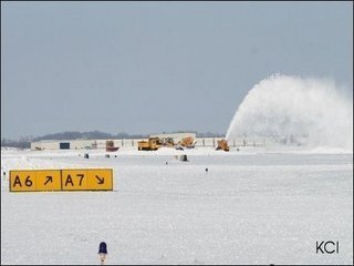 1976 Ford Bronco - Snow blower operating on an airfield with buildings and signage visible.