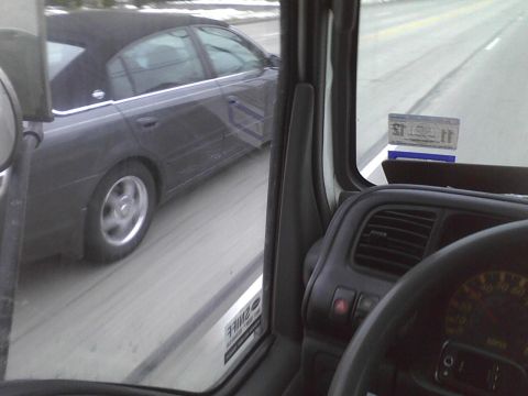 2003 Ford Crown Victoria - A dark sedan is seen from the perspective of a driver on a road.