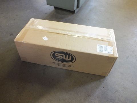 2003 Ford Crown Victoria - long taped cardboard box bearing the SW Stainless Works exhaust-products logo rests on a shop floor.