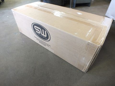 2003 Ford Crown Victoria - Large flat Stainless Works exhaust product box, shrink-wrapped, sitting on concrete shop floor.