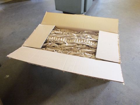 2003 Ford Crown Victoria - Opened shipping box showing kraft paper void fill protecting a stainless steel exhaust component.