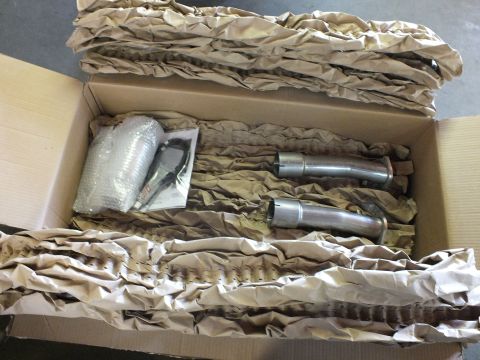 2003 Ford Crown Victoria - Two polished stainless collector pipes beside bubble-wrapped parts and a paper manual in a box.