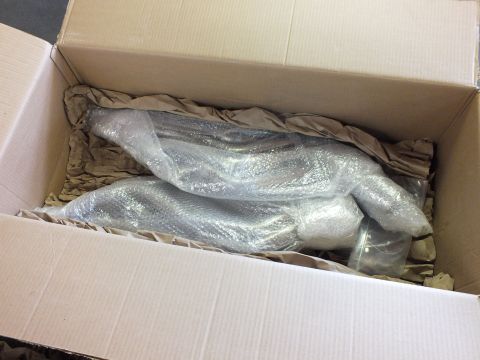 2003 Ford Crown Victoria - Two bubble-wrapped tubular exhaust headers nested in kraft paper packing inside an open box.