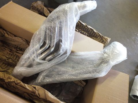 2003 Ford Crown Victoria - Two long-tube stainless headers, partly unwrapped, showing four merged primary tubes each.