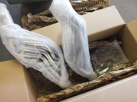 2003 Ford Crown Victoria - Two unwrapped tubular headers next to a bag of stainless collectors and clamps in a box.