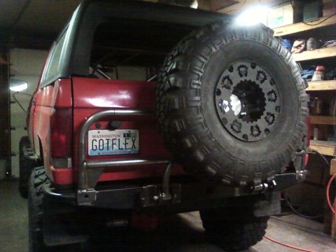 1989 Ford Bronco - The rear of a red SUV is shown, a spare tire mounted on a custom bumper and a Washington license plate.