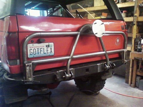 1989 Ford Bronco - Rear view of a red SUV a custom tube swing down tire carrier and a personalized Washington license plate.