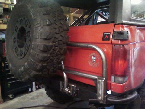 1989 Ford Bronco - Rear view of a 1989 Ford Bronco showing a custom spare tire carrier and large off-road tire.