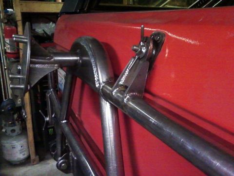 1989 Ford Bronco - Close-up of a custom-fabricated swing-down tire carrier mount, showing welded steel tubing construction.